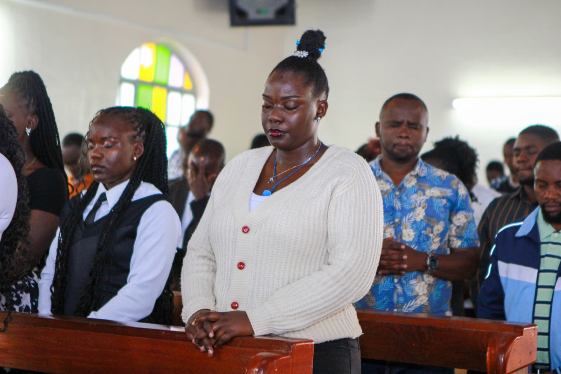 Young people standing together in prayer during the church service
